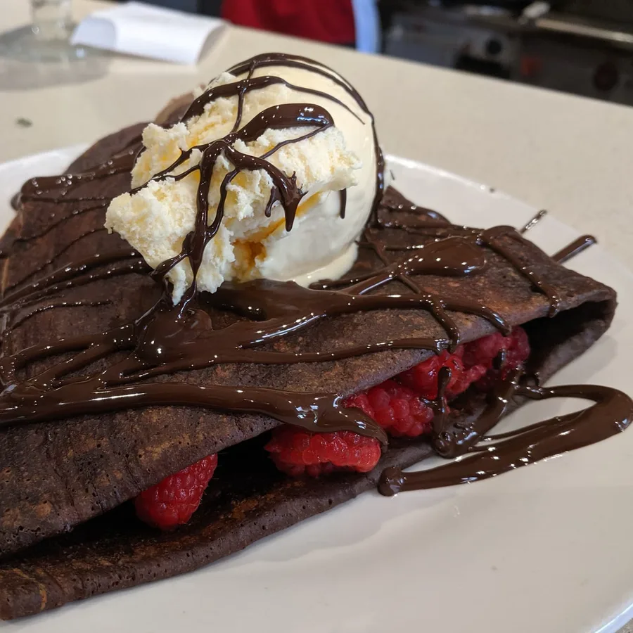Chocolate crepe filled with raspberries and topped with ice cream